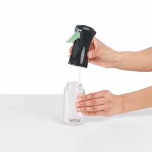 Aceitera de spray en uso, pulverizando aceite sobre una ensalada